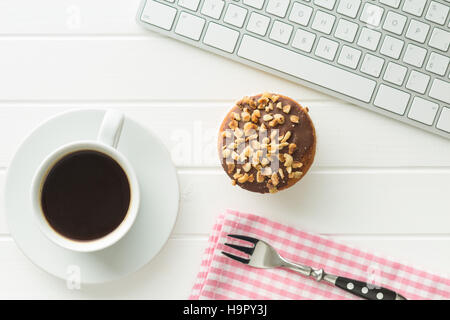 Break for coffee and muffin at the office. Concept with coffee, muffin and computer keyboard. Stock Photo
