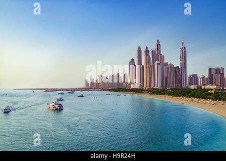 View of boats in front of skyline of modern skyscrapers and beach at Marina district of Dubai United Arab Emirates, UAE Stock Photo