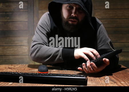hacker in the black hood in a room with wooden walls Stock Photo