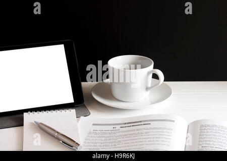 Workplace for planning finance,data book,notepad and a cup of coffee on white wooden table in front of grunge black background. Stock Photo