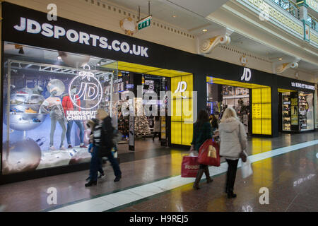 People passing JD sports King of Trainers at INTU Trafford Centre  Manchester. UK  25th November, 2016. Black Friday Sales Offers Weekend.  City centre holiday shopping season, retail shops, stores, modern, style, bargains, business brands, fashion, advertising, person, consumer, Christmas shoppers, people discount sale shopping, and consumer spending on Black Friday weekend considered to be the biggest shopping event of the year.   U.K. retailers have embraced the U.S. post-holiday sale bonanza, even though many customers were left surprised by wall-to-wall discounts in their favourite stores Stock Photo
