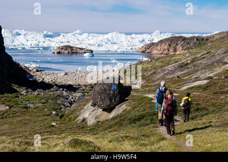 People hiking on blue trail hike to Holms Bakke Ilulissat Icefjord (Isfjord) with enormous icebergs in summer 2016. Ilulissat West Greenland Stock Photo