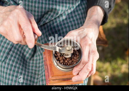 Senior woman grinding coffee on a vintage coffee grinder Stock Photo