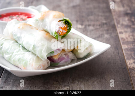 Vietnamese rolls with vegetables, rice noodles and prawns on wooden background Stock Photo