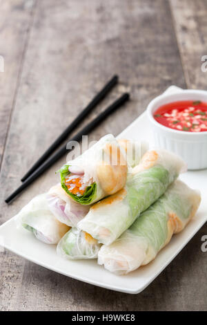 Vietnamese rolls with vegetables, rice noodles and prawns on wooden background Stock Photo