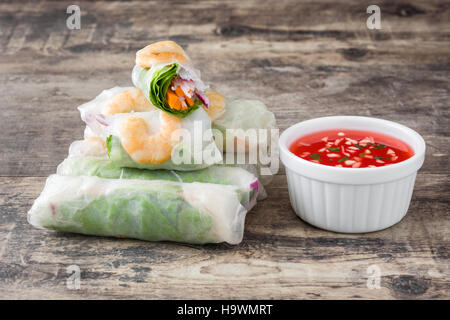 Vietnamese rolls with vegetables, rice noodles and prawns on wooden background Stock Photo