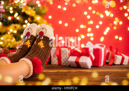 Detail of woman feet in woolen socks, blur Christmas tree on background Stock Photo