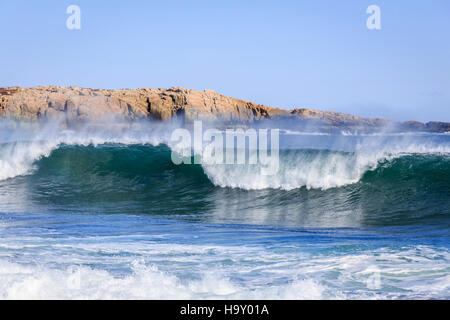 This image captures the powerful force of crashing waves along a rugged coastline. The dynamic natural event showcases the beauty and energy of coastal ecosystems. Stock Photo