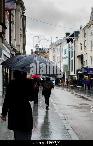 Exeter, England, UK - 22 November 2016: Unidentified people walk on High Street in typical British rainy weather. Stock Photo