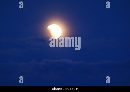A photograph of the total lunar eclipse on April 14, 2014, taken over a scenic landscape. The image captures the dramatic transition of the moon's phases during the eclipse, offering a striking view of this celestial event. Stock Photo