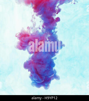 Color drop underwater creating a silk drapery. Ink swirling underwater. Cloud of colorful ink. Blue and magenta mix into violet Stock Photo