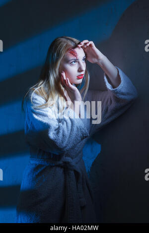 Concept: victim, accident, domestic violence. Beautiful young woman in bathrobe suffer head trauma in dramatic light. Stock Photo