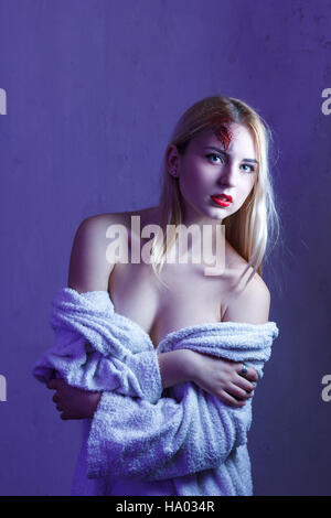 Concept: victim, accident, domestic violence. Beautiful young woman in bathrobe suffer head trauma in dramatic light. Stock Photo