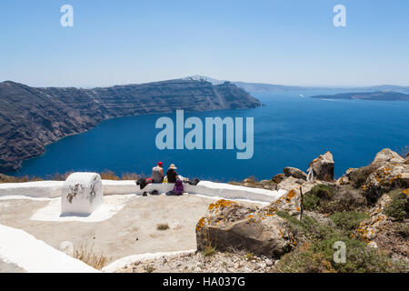 Hikers taking a break on a terrasse overlooking the sea at the Church of Panagia on the trail to Oia from Thira Stock Photo