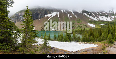 Panorama of Snow Melting around Iceberg Lake with thick fog above Stock Photo