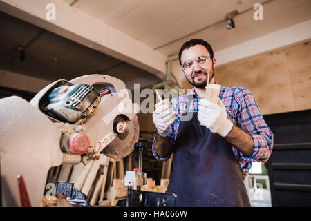 Carpenter working on an electric buzz saw cutting some boards, he is wearing safety glasses Stock Photo