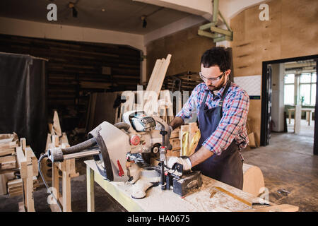 Young craftsman in uniform working at carpentry Stock Photo