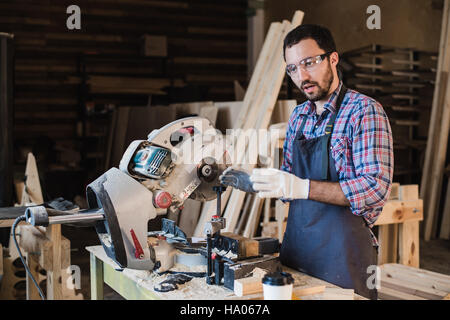Young craftsman in uniform working at carpentry Stock Photo