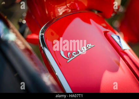 Close-up of the Vespa logo on a bright red Vespa motor scooter parked outside on a street in the sun Stock Photo