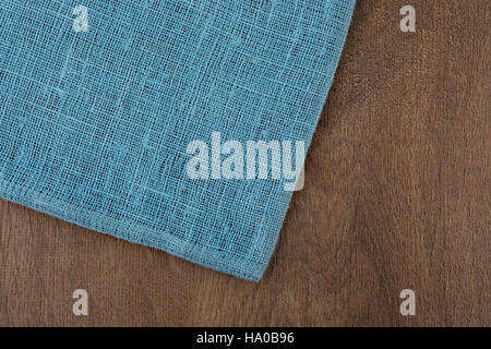 Napkin from left side wooden table. Soft blue woven linen fabric texture / wood texture. Coarse jute sack. Top view background. Stock Photo