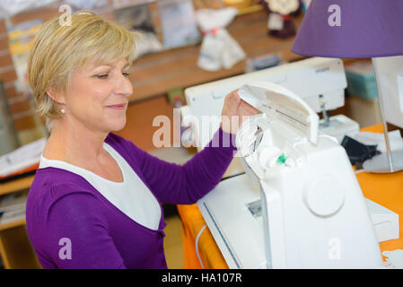 Mature lady using sewing machine Stock Photo