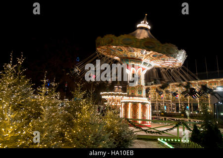 The brightly lit Swing Carousel on a dark winter evening during the Christmas Market in the Tivoli Gardens, Copenhagen, Denmark. Stock Photo