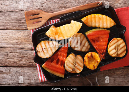 Delicious fruit apples, melon, pear, watermelon and peach on a grill pan close-up on the table. horizontal view from above Stock Photo