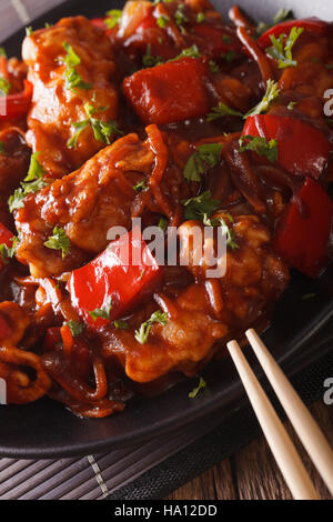 Pork braised in sweet and sour sauce with vegetables close-up in an Asian style. vertical Stock Photo