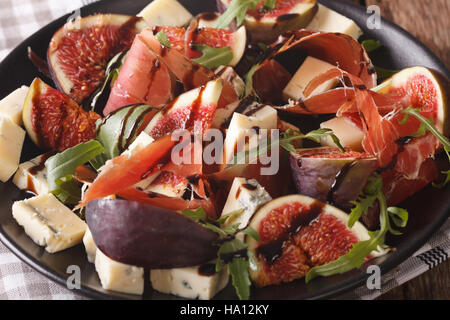 Salad with figs, prosciutto, cheese and arugula macro on a plate on the table. horizontal Stock Photo