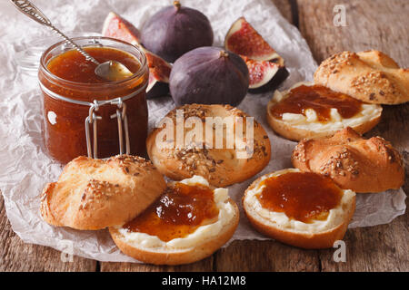 Glass jar with some fig jam and sweet buns close-up on the table. Horizontal Stock Photo