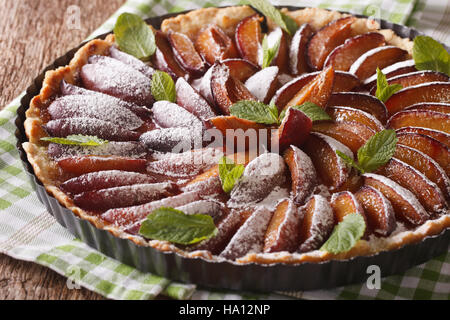 Delicious pastry: plum tart with mint and powdered sugar close-up on the table. horizontal Stock Photo