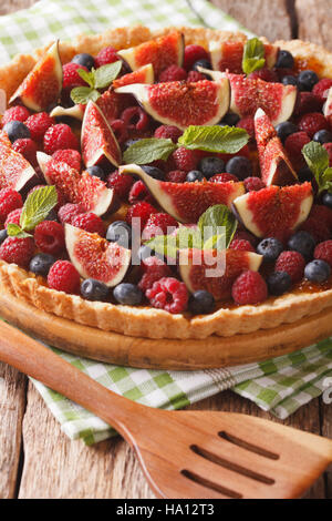 Delicious pastry: tart with fresh figs, raspberries and blueberries close-up on the table. Vertical Stock Photo