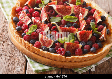 Delicious pastry: tart with fresh figs, raspberries and blueberries close-up on the table. horizontal Stock Photo
