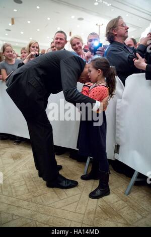 U.S. President Barack Obama bends down to hear a personal message from a young girl during the U.S. Embassy meet and greet at Hotel Adlon November 16, 2016 in Berlin, Germany. Stock Photo