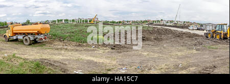 Orange vintage tank truck is parked on building site. Panoramic view on landscape transform into urban area. Stock Photo