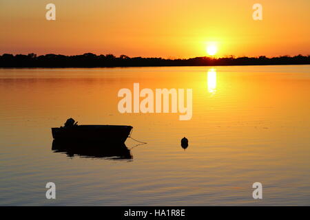 Sunrise and a boat at its mooring on Pumicestone Passage off Golden Beach, Caloundra on the Sunshine Coast of Queensland Stock Photo