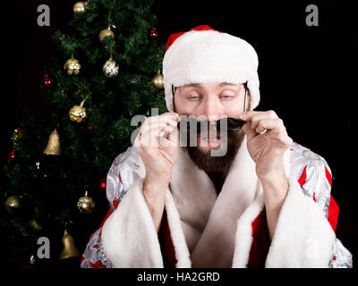 bad rastoman Santa Claus holds round glasses and smiles, on the background of Christmas tree. different funy emotions Stock Photo