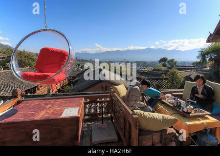 Lijiang, China - November 10, 2016: People relaxing on a couch and enjoying the view of Lijiang Old Town on a sunny day Stock Photo