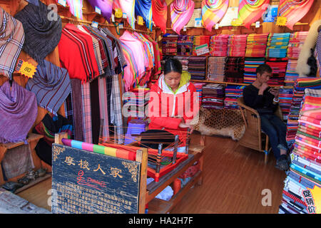 Lijiang, China - November 10, 2016: Mosuo woman weaving inside her whorshop in Lijiang Old Town, Yunnan Stock Photo