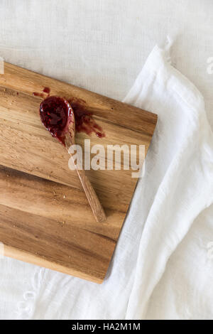 Wooden spoon covered in jam on chopping board Stock Photo