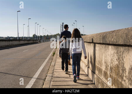 Father and two children walking down street Stock Photo