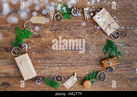 Christmas gifts, tags, pine cones, pine leaves, cinnamon sticks and dried orange slices in a circle Stock Photo