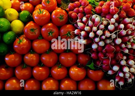 Close-up of radishes, tomatoes, lemon and limes on a market stall Stock Photo