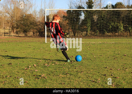 Boy practicing taken penalty kick on a football pitch, England, UK Stock Photo