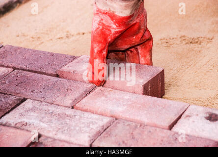 Gloved hand laying brick pavers Stock Photo
