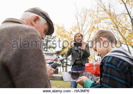 Senior man and grandson with model airplane remote control and digital tablet in park