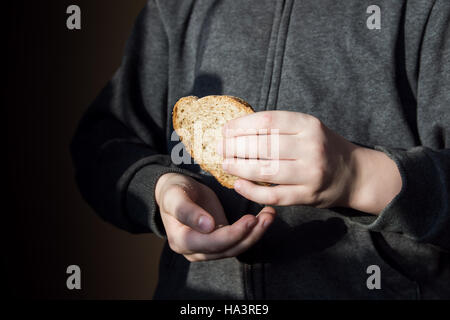 Piece of bread in children hands. Hunger and helping concept. Stock Photo