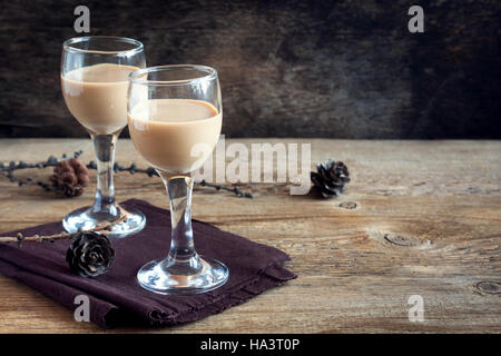 Irish cream coffee liqueur, Christmas decoration and cones over rustic wooden background - homemade festive Christmas alcoholic drink Stock Photo