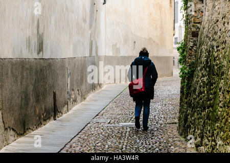 A woman walks along a narrow cobbled street in Citta Alta, Bergamo, Italy Stock Photo