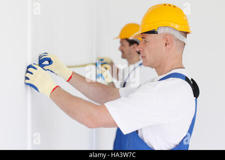 Building teamwork concept - group of smiling builders in hardhats with tools indoors Stock Photo